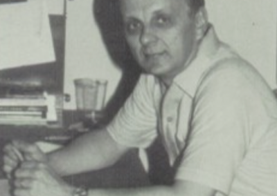 Ron Underwood seated at his desk at Beyer High School in the 1970s, focused on his work as a speech and debate coach.